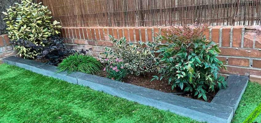 Bordillo de pizarra natural delimitando grava y césped