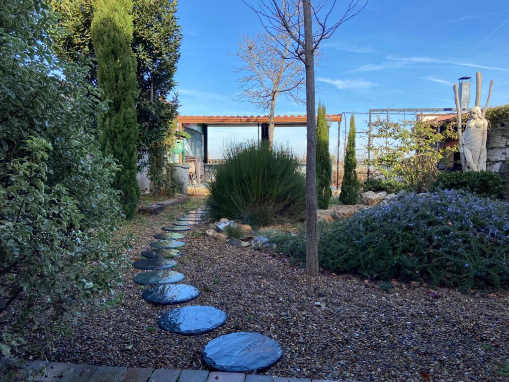 Jardín mediterráneo con grava y vegetación.