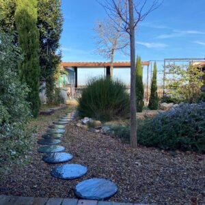 Jardín mediterráneo con grava y vegetación.