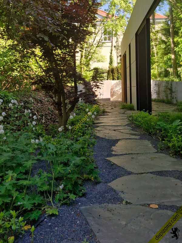 Losas irregulares de pizarra natural en el pasillo exterior entre la vivienda y el jardín